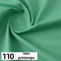 Gros plan sur une popeline de coton vert clair et lisse de Longan Craft France avec de légers plis. En bas à gauche, une case blanche indique "110" et "Vert printemps". Parfait pour les chemises, les robes, les doublures et bien plus encore.