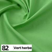 Gros plan sur la Popeline de coton au mètre de Longan Craft France, lisse et vert clair, avec de légers plis. Une étiquette blanche au bas de l'emballage indique le numéro 82 et le texte "Vert herbe.
