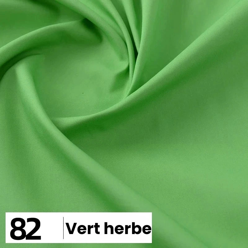 Gros plan sur la Popeline de coton au mètre de Longan Craft France, lisse et vert clair, avec de légers plis. Une étiquette blanche au bas de l'emballage indique le numéro 82 et le texte "Vert herbe.