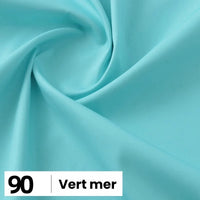 Gros plan sur une popeline de coton turquoise clair et lisse de Longan Craft France, présentant de légers plis. En bas à gauche, une étiquette indique "90" et "Vert mer". Convient pour les chemises, les robes, les doublures - disponible au mètre.