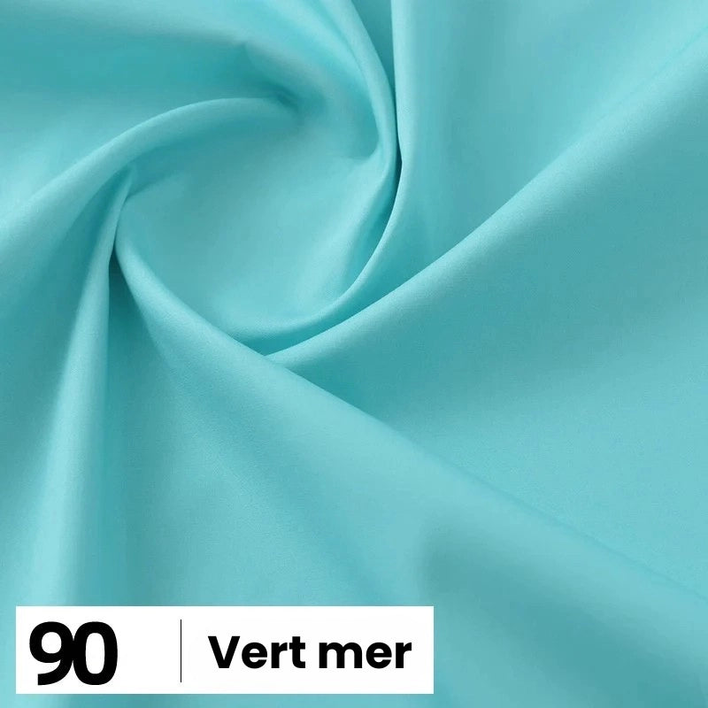 Gros plan sur une popeline de coton turquoise clair et lisse de Longan Craft France, présentant de légers plis. En bas à gauche, une étiquette indique "90" et "Vert mer". Convient pour les chemises, les robes, les doublures - disponible au mètre.