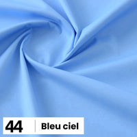 Gros plan sur une "Popeline de coton au mètre" bleu clair de Longan Craft France, disposée en plis souples, avec une étiquette blanche marquée 44 et "Bleu ciel" dans le coin inférieur gauche.