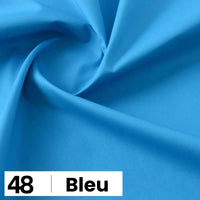 Gros plan sur la Popeline de coton au mètre de Longan Craft France, d'un bleu vif et lisse, légèrement tourbillonnante. Une étiquette blanche en bas indique "48 | Bleu" en texte noir. Parfait pour les chemises, les robes et les doublures.