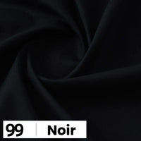 Gros plan sur une popeline de coton noire et lisse de Longan Craft France, disposée en plis souples. Une étiquette en bas à gauche indique "99 | Noir" en noir et blanc, mettant en valeur cette douce et légère popeline parfaite pour chemises et robes.