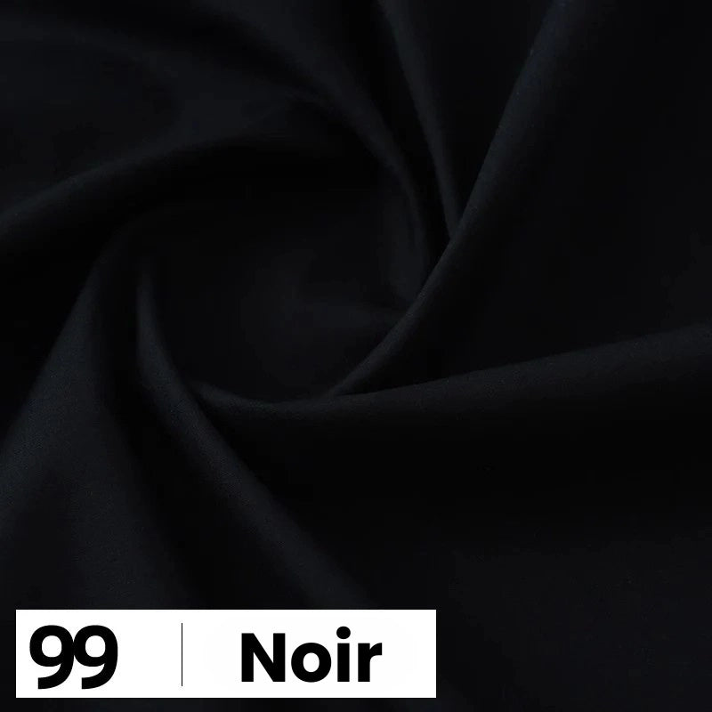 Gros plan sur une popeline de coton noire et lisse de Longan Craft France, disposée en plis souples. Une étiquette en bas à gauche indique "99 | Noir" en noir et blanc, mettant en valeur cette douce et légère popeline parfaite pour chemises et robes.