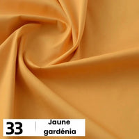 Un gros plan de la Popeline de coton au mètre jaune clair et lisse de Longan Craft France montre des plis doux. La mention "33 | Jaune gardénia" est inscrite en noir sur blanc en bas à gauche. Cette popeline de coton souple convient aux chemises, aux robes et aux doublures.