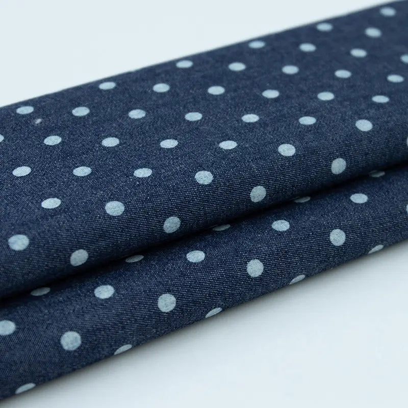 Gros plan sur deux pièces pliées du Tissu denim coton imprimé de fleurs et d'étoiles au mètre de Longan Craft France, un tissu denim imprimé léger, idéal pour la confection de vêtements.