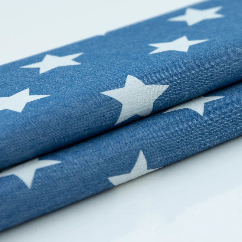 Deux pièces de Tissu denim coton imprimé de fleurs et d'étoiles au mètre par Longan Craft France, pliées proprement - idéal pour réaliser des vêtements ou des projets créatifs avec ce denim imprimé léger.