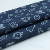 Gros plan sur le coton denim bleu foncé de Longan Craft France, avec un imprimé floral et étoilé bleu clair. Ce léger tissu denim imprimé est plié, parfait pour les vêtements qui souhaitent une touche ludique.