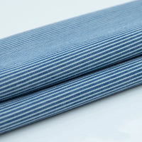 Gros plan sur deux pièces pliées de Tissu denim coton imprimé de fleurs et d'étoiles par Longan Craft France, mettant en valeur le tissu denim imprimé bleu clair et blanc sur un fond blanc uni.