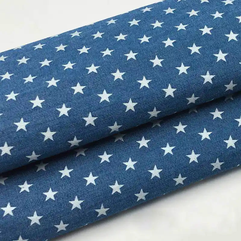 Tissu denim coton léger imprimé de fleurs et d'étoiles, vendu au mètre par Longan Craft France, idéal pour vêtements ou projets créatifs.