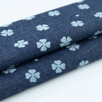 Un gros plan du tissu denim coton imprimé de fleurs et d'étoiles de Longan Craft France montre le motif charmant sur tissu léger, présenté plié pour afficher le design sur les deux couches.
