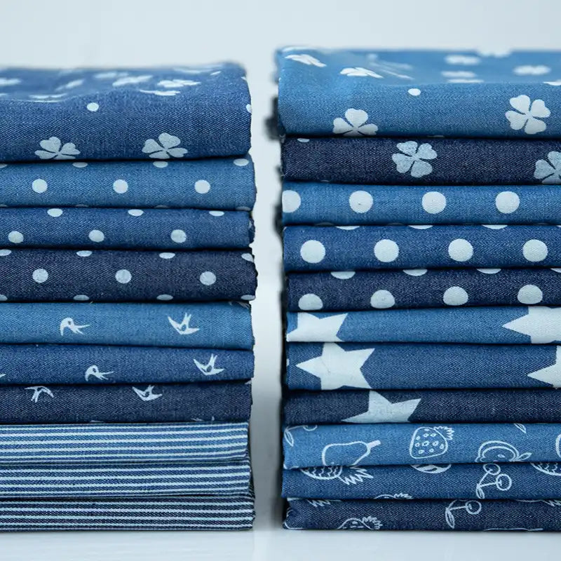 Stacks of Longan Craft France tissu denim coton léger imprimé de fleurs et d'étoiles sont alignées sur une surface blanche-idéal pour vos créations vestimentaires. Denim imprimé vendu au mètre.
