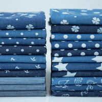 Stacks of Longan Craft France tissu denim coton léger imprimé de fleurs et d'étoiles sont alignées sur une surface blanche-idéal pour vos créations vestimentaires. Denim imprimé vendu au mètre.