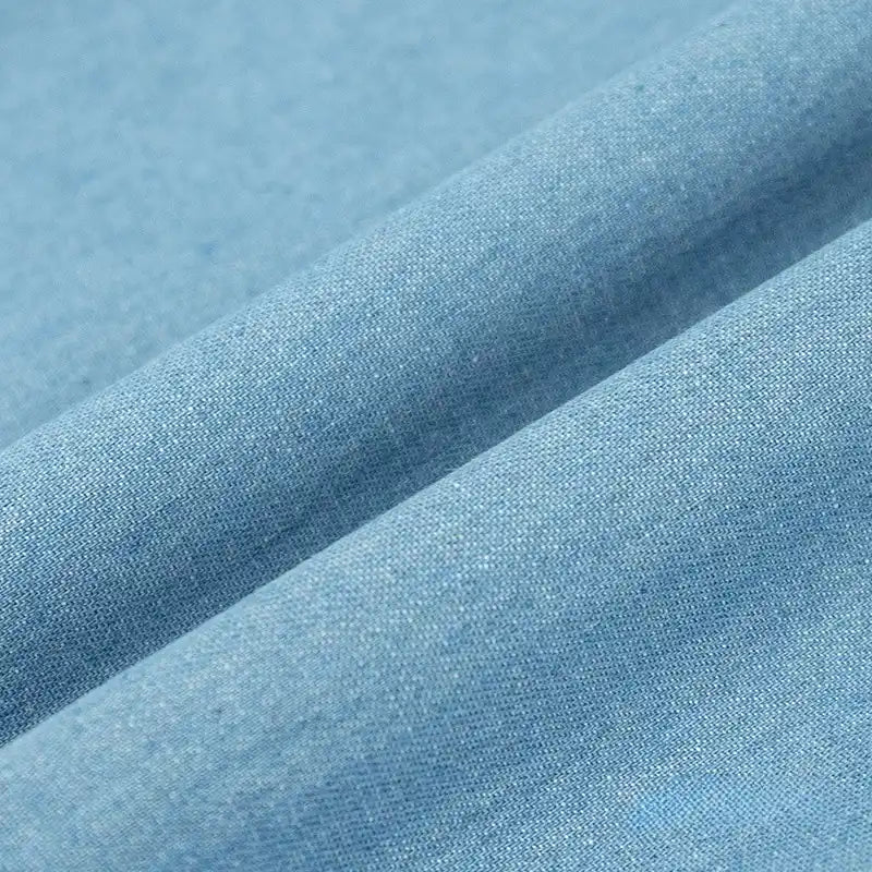 Gros plan sur le Tissu denim délavé 6 oz au mètre de Longan Craft France, un tissu jean en coton doux de couleur bleu clair, à la texture lisse et au tissage visible, présenté avec de légers plis.