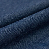 Gros plan sur le Tissu denim délavé 6 oz au mètre de Longan Craft France, montrant la texture tissée et les fils fins du tissu de coton bleu doux. Le tissu légèrement plié crée un pli visible sur l'image.