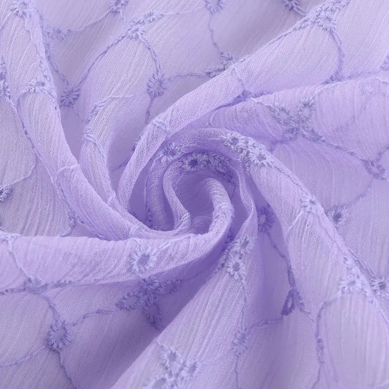 Gros plan sur le Tissu voile froissé au mètre de Longan Craft France, un voile de polyester violet clair brodé à motifs floraux vintage, assemblé en un tourbillon-idéal pour la confection de vêtements légers et de rideaux.
