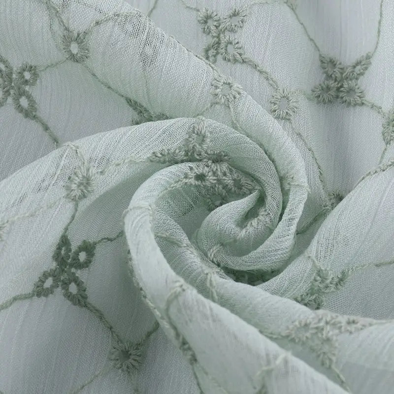 Gros plan sur le Tissu voile froissé au mètre de Longan Craft France : voile de polyester vert clair avec broderie florale vintage, délicate et fluide - idéal pour les vêtements d'été ou les rideaux.