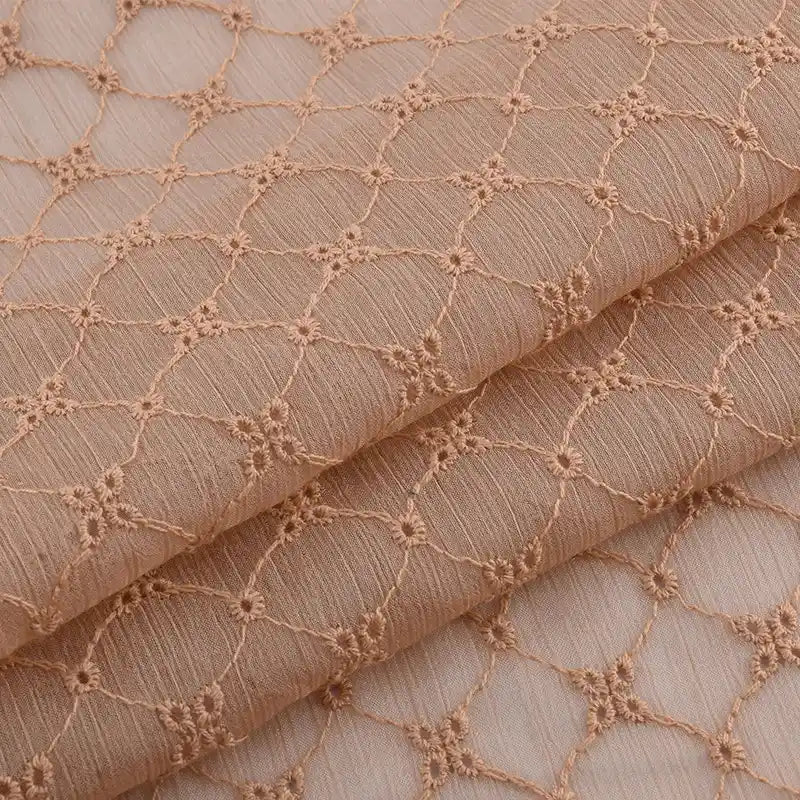 Gros plan sur le Tissu voile froissé au mètre de Longan Craft France, un voile de polyester brun clair brodé de motifs floraux vintage et d'un délicat treillis de diamants, parfait pour les vêtements d'été ou les rideaux.