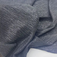 Gros plan sur le Tissu lamé froissé au mètre de Longan Craft France - tissu polyester gris foncé métallisé à la surface froissée et texturée et aux plis naturels, parfait pour les costumes de scène, les robes et la couture.
