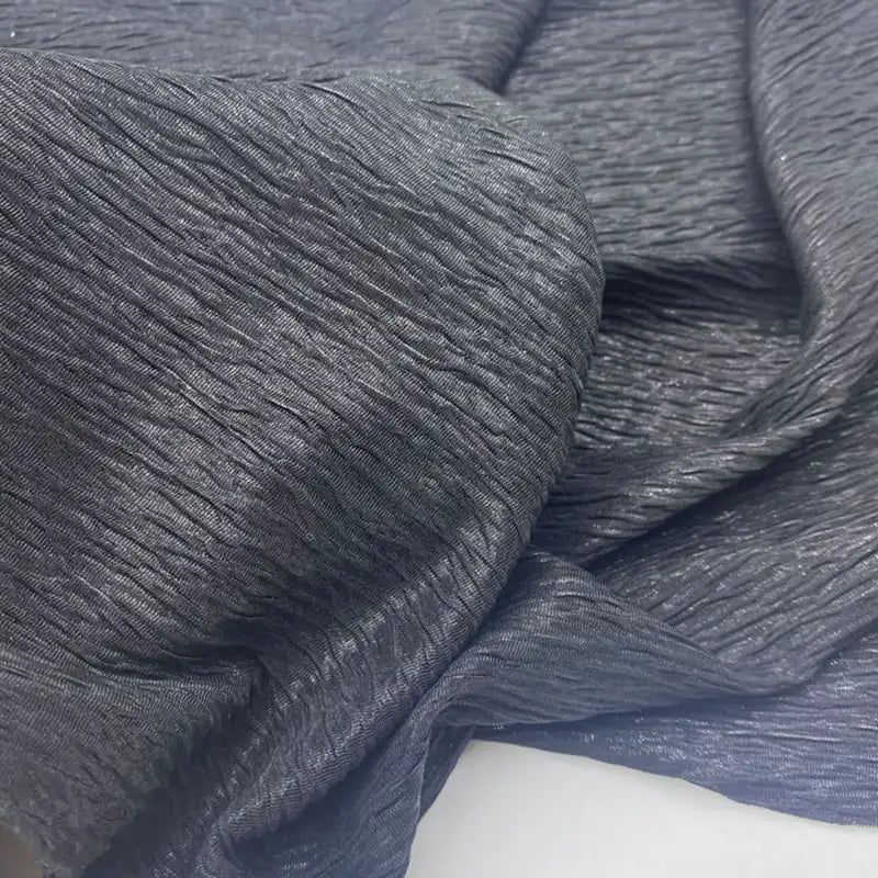 Gros plan sur le Tissu lamé froissé au mètre de Longan Craft France - tissu polyester gris foncé métallisé à la surface froissée et texturée et aux plis naturels, parfait pour les costumes de scène, les robes et la couture.