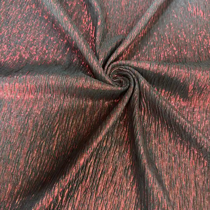 Gros plan sur le tissu lamé froissé au mètre de Longan Craft France, composé de polyester métallisé noir et rouge à la texture froissée et à la finition mate et brillante - un tissu parfait pour les costumes, les robes et la couture.