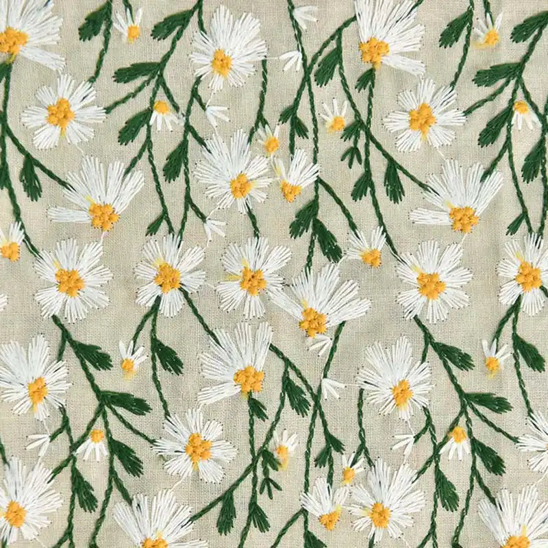 Des fleurs brodées blanches et jaunes avec des tiges vertes ornent le Tissu ramie marguerite au mètre beige de Longan Craft France, un tissu doux en coton-ramie idéal pour les robes, les rideaux, la couture et les projets créatifs.