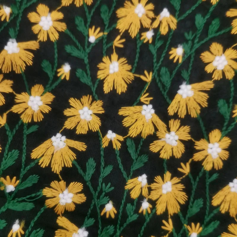 Gros plan sur le tissu ramie marguerite au mètre de Longan Craft France, brodé de fleurs jaunes et de tiges vertes sur fond noir - un tissu coton-ramie polyvalent idéal pour les peignoirs, les rideaux, la couture ou les projets créatifs.