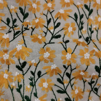 Des fleurs jaunes et blanches aux tiges vertes sont brodées sur le Tissu ramie marguerite de Longan Craft France, un tissu doux idéal pour les robes, la couture créative ou les rideaux.