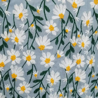 Le Tissu ramie marguerite au mètre de Longan Craft France présente des marguerites blanches brodées sur du coton ramie bleu clair, un tissu doux et polyvalent idéal pour les robes, les projets créatifs ou les rideaux.
