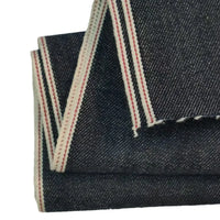 Tissu en jean selvedge bleu profond 14 oz de Longan Craft France, 100 % coton, révèle une bordure blanche et rouge nette sur fond uni, idéal pour confectionner des jeans.
