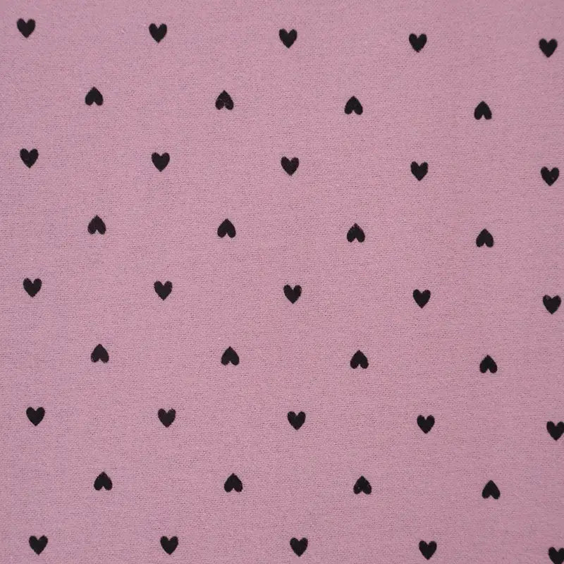 La Flanelle de coton à motifs cœurs de Longon Craft France présente un fond rose avec des petits cœurs noirs, parfaits pour la couture douillette, le quilting ou les projets créatifs. Tissu de flanelle doux et confortable vendu au mètre.