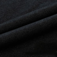 Gros plan sur le Tissu en jean extensible au mètre (8 oz) de Longan Craft France : un denim noir extensible à la texture fine, au tissage visible et à la brillance subtile. Les plis diagonaux soulignent l'élasticité du tissu, idéal pour les jeans et les vêtements.