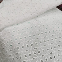 Gros plan sur le Voile de coton brodé au mètre de Longan Craft France : tissu blanc avec broderie florale ajourée, idéal pour les robes, la couture et la décoration. Ce tissu léger et transparent est parfait pour des créations élégantes.