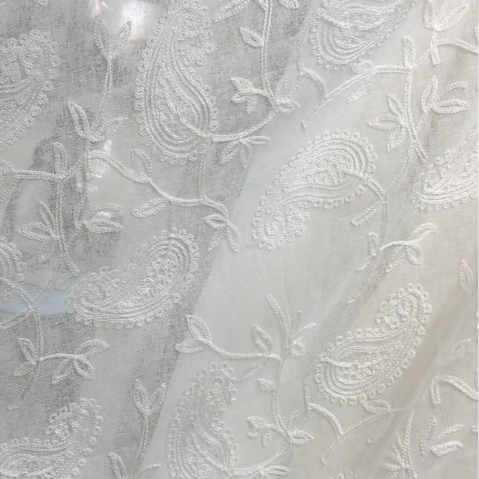Gros plan sur le Tissu brodé floral en gaze de lin au mètre de Longan Craft France, un tissu de lin naturel transparent avec des motifs de paisley et de vigne brodés en blanc, idéal pour les vêtements d'été.