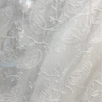 Gros plan sur le Tissu brodé floral en gaze de lin au mètre de Longan Craft France, un tissu de lin naturel transparent avec des motifs de paisley et de vigne brodés en blanc, idéal pour les vêtements d'été.