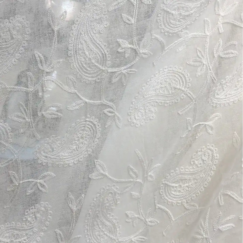 Gros plan sur le Tissu brodé floral en gaze de lin au mètre de Longan Craft France, un tissu de lin naturel transparent avec des motifs de paisley et de vigne brodés en blanc, idéal pour les vêtements d'été.