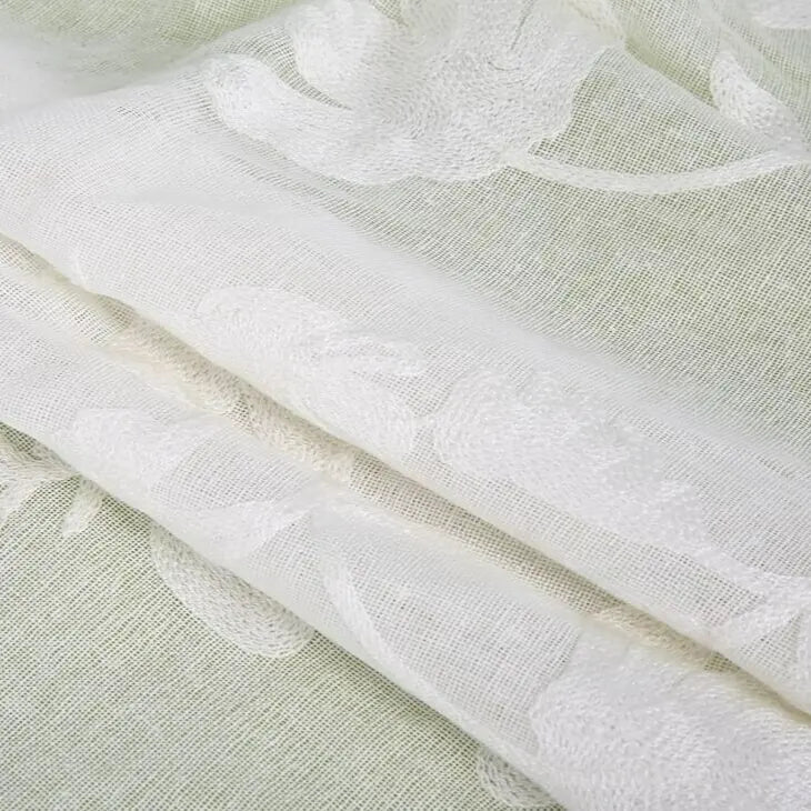 Gros plan sur Tissu brodé floral en gaze de lin au mètre de Longan Craft France : un tissu naturel, fin et transparent, à motif floral subtil-idéal pour vêtements d'été élégants ou habits de bébé.