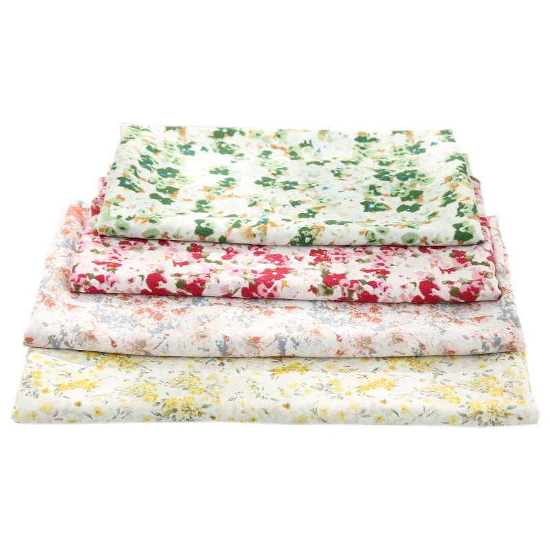 Quatre pièces vibrantes de Tissu mousseline à fleurs de Longan Craft France, présentant des imprimés floraux verts, roses, rouges et jaunes sur du polyester pour vêtements, sont empilées sur un fond blanc.