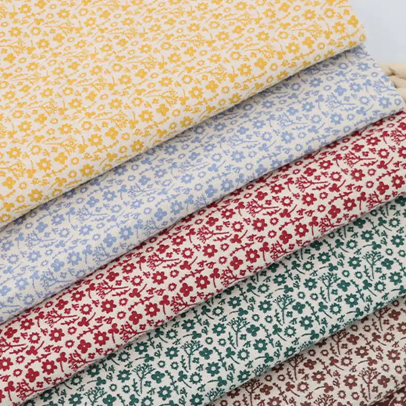 Quatre pièces de "Flanelle de coton fleurie au mètre" de Longan Craft France, présentant des imprimés floraux d'automne colorés sur du coton flanelle blanc, sont soigneusement empilées - idéales pour coudre des robes, des vêtements et des projets créatifs.