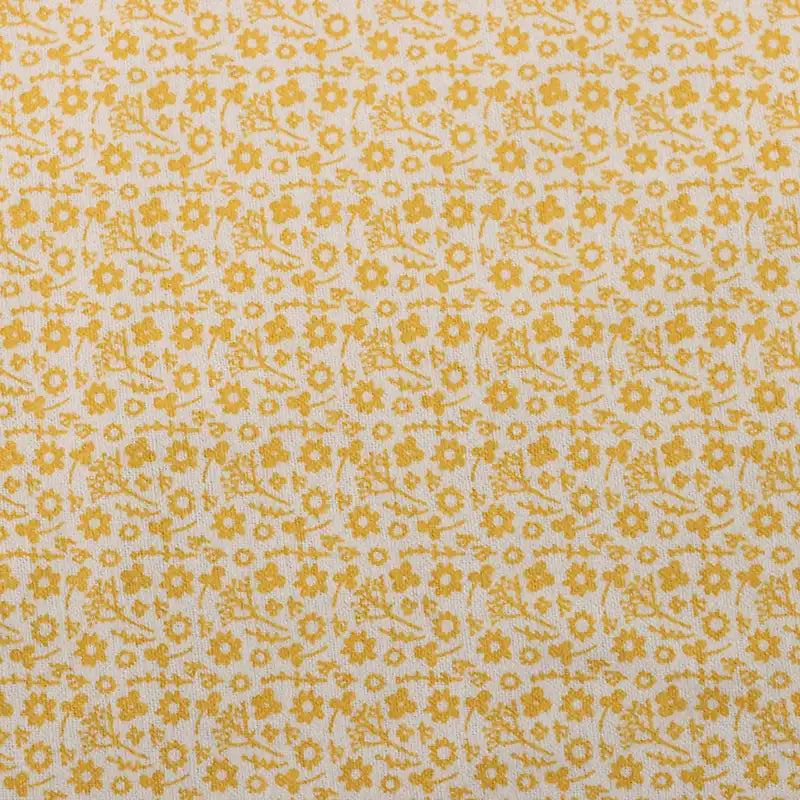 Un gros plan de la Flanelle de coton fleurie au mètre de Longan Craft France montre son tissu beige clair avec de petites fleurs et feuilles jaunes dans un motif automnal régulièrement espacé, parfait pour coudre des robes, des vêtements ou des travaux créatifs.