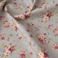 Gros plan sur la Popeline de coton à fleurs au mètre de Longan Craft France : tissu gris clair 100% coton pour le quilting, avec un imprimé floral - roses roses et rouges, feuilles vertes, fleurs jaunes et bleues - doux et légèrement froissé.