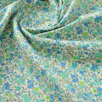 Gros plan sur Popeline de coton à fleurs au mètre de Longan Craft France, un tissu doux 100 % coton à l'imprimé floral bleu et vert, délicatement froncé pour mettre en valeur sa texture naturelle - parfait pour le quilting, les nappes, les robes et les chemises.