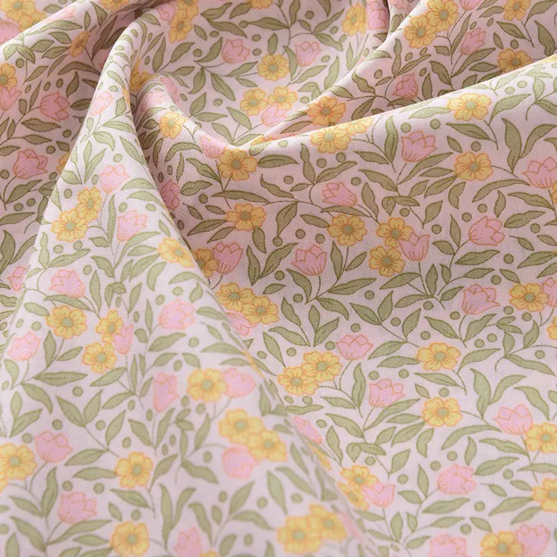 Un gros plan de Popeline de coton à fleurs au mètre de Longan Craft France montre son impression florale douce et lisse - tissu idéal pour le quilting, les langes, les peignoirs et les chemises.