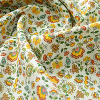 Gros plan sur la Popeline de coton à fleurs au mètre de Longan Craft France, un tissu 100% coton doux imprimé floral coloré, idéal pour quilting, nappes, robes et chemises. Petites fleurs jaunes, oranges et vertes sur fond clair.