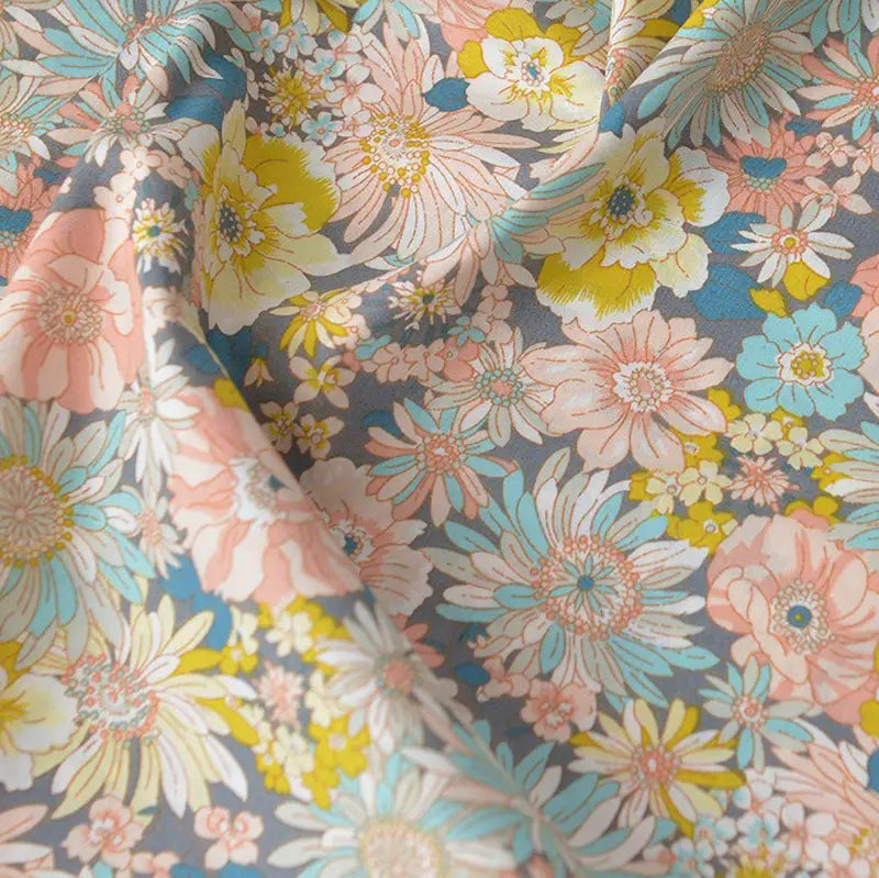 Gros plan sur Popeline de coton à fleurs au mètre de Longan Craft France, un tissu floral doux 100 % coton avec des fleurs roses, jaunes, bleues et blanches sur fond gris, idéal pour le quilting, les nappes, les robes et les chemises.
