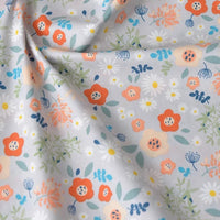 Gros plan sur la Popeline de coton à fleurs au mètre de Longan Craft France, un tissu floral doux 100 % coton avec des fleurs orange et blanches, des feuilles vertes et des accents bleus sur un fond clair - idéal pour le quilting, les nappes, les robes ou les chemises.