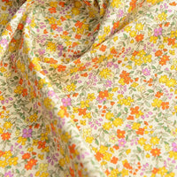 Gros plan sur Popeline de coton à fleurs de Longan Craft France, un tissu doux 100 % coton avec un imprimé floral coloré - fleurs jaunes, orange, violettes et rouges avec des feuilles vertes - idéal pour le quilting, les nappes, les robes et les chemises.