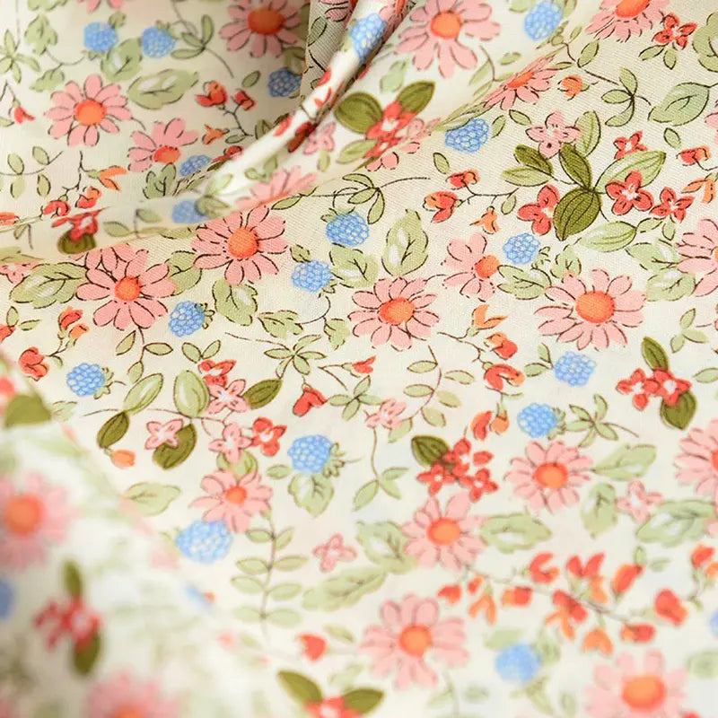 Gros plan sur la Popeline de coton à fleurs au mètre de Longan Craft France : tissu 100% coton doux, imprimé floral beige avec fleurs roses et corail, feuilles vertes et accents bleus. Idéal pour quilting, nappes, robes ou chemises.