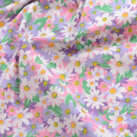 Gros plan sur Popeline de coton à fleurs au mètre de Longan Craft France, montrant un imprimé floral coloré avec des marguerites et des feuilles sur un tissu 100% coton violet clair, légèrement froissé - idéal pour le quilting, les nappes, les robes et les chemises.